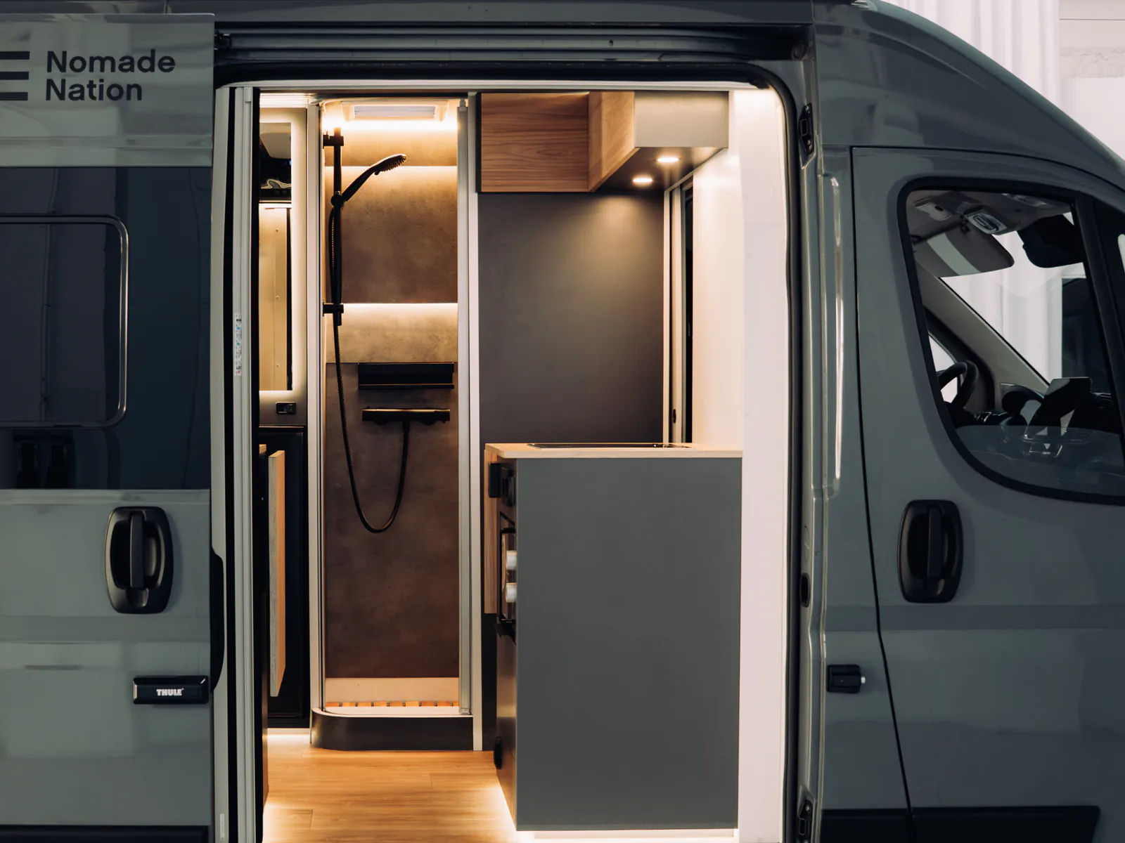 La porta lateral oberta, amb la dutxa interior i l'armari a la vista